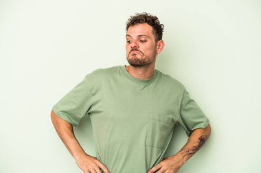 Yeşil arka planda izole edilmiş genç beyaz adam hedeflere ve amaçlara ulaşmayı hayal ediyor.