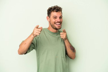 Yeşil arka planda izole edilmiş genç beyaz adam. Önü gösteren neşeli gülümsemeler..