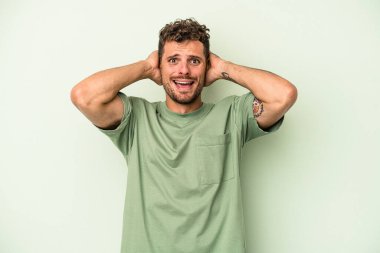 Yeşil arka planda izole edilmiş genç beyaz adam öfkeyle bağırıyor..