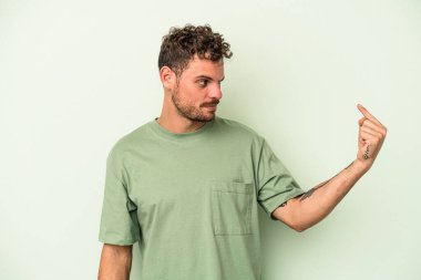 Yeşil arka planda izole edilmiş genç beyaz adam sanki seni davet ediyormuş gibi seni işaret ediyor..