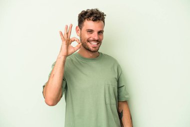 Genç beyaz adam yeşil arka planda izole edilmiş neşeli ve kendinden emin..