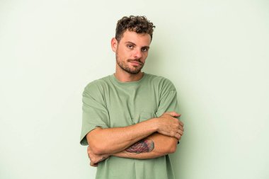 Yeşil arka planda izole edilmiş genç beyaz adam sıkılmış, yorgun ve dinlenmeye ihtiyacı var..