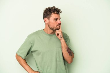 Yeşil arka planda izole edilmiş genç beyaz bir adam ya sır saklıyor ya da sessizlik istiyor..