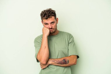 Yeşil arka planda izole edilmiş genç beyaz adam tekrarlanan bir görevden yoruldu..