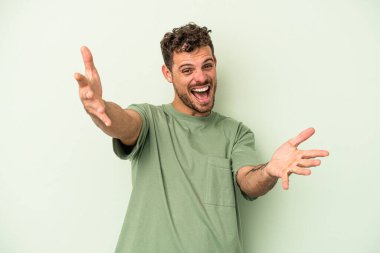 Yeşil arka planda izole genç beyaz adam kameraya sarıldığı için kendinden emin hissediyor..
