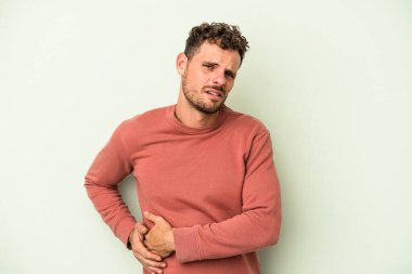 Yeşil arka planda karaciğer ağrısı çeken, karnı ağrıyan genç beyaz bir adam..