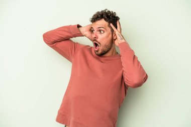 Genç beyaz adam yeşil arka planda izole edilmiş bağırıyor, çok heyecanlı, tutkulu, bir şeyden memnun..