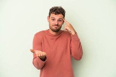 Kafkasyalı genç adam yeşil arka planda izole edilmiş ve elinde bir ürün tutuyor..