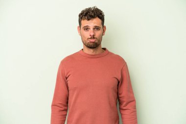 Kafkasyalı genç adam yeşil arka planda izole edilmiş üzgün, ciddi yüzlü, mutsuz ve hoşnutsuz..