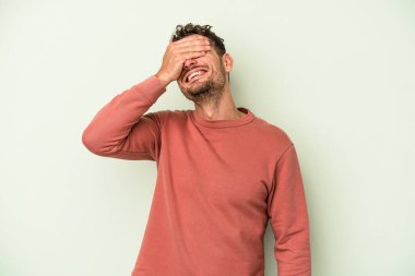 Yeşil arka planda izole edilmiş genç beyaz adam ellerini başının üstünde tutarak neşe içinde gülüyor. Mutluluk kavramı.