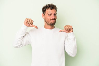 Yeşil arka planda izole genç beyaz adam gururlu ve kendinden emin hissediyor, örnek olarak..