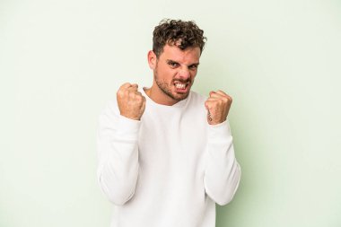 Yeşil arka planda izole edilmiş genç beyaz adam gergin elleriyle çığlık atıyor..