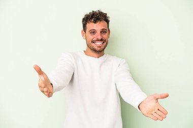 Yeşil arka planda izole edilmiş beyaz bir genç hoş bir yüz ifadesi sergiliyor..