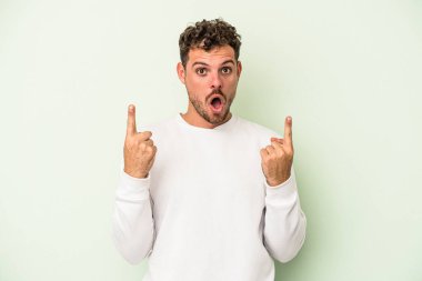 Yeşil arka planda izole edilmiş beyaz bir adam ağzı açık bir şekilde üst tarafı işaret ediyor..