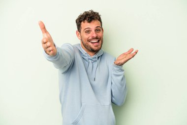 Yeşil arka planda izole genç beyaz adam kameraya sarıldığı için kendinden emin hissediyor..