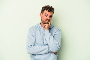 Kafkasyalı genç bir adam yeşil arka planda izole edilmiş. Bir strateji planlıyor, bir iş yolu düşünüyor..