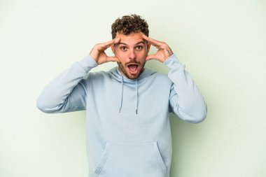 Yeşil arka planda izole genç beyaz adam hoş bir sürpriz alıyor, heyecanlı ve el kaldırıyor..