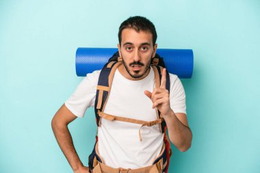 Kafkasyalı genç yürüyüşçü mavi arka planda izole edilmiş. Bir fikri var, ilham verici bir kavram..