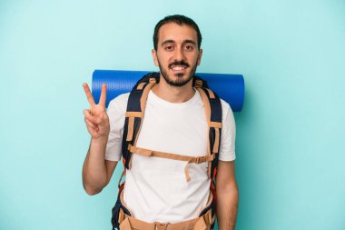 Genç beyaz yürüyüşçü, mavi arka planda iki numarayı parmaklarıyla gösteriyor..