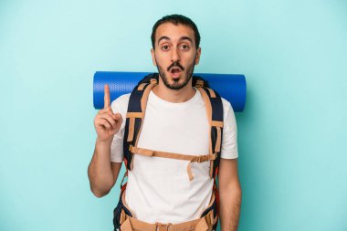 Kafkasyalı genç yürüyüşçü, mavi arka planda izole edilmiş. Harika bir fikri var, yaratıcılık kavramı..