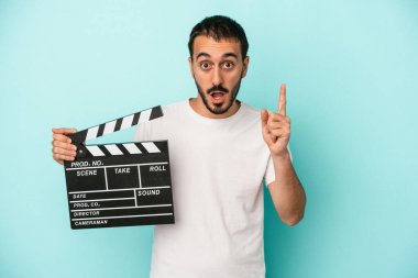 Kafkasyalı genç aktör elinde klaket tutarken mavi arka planda bir fikri, ilham konsepti vardı..