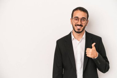 Beyaz arka planda izole edilmiş beyaz iş adamı gülümsüyor ve başparmağını kaldırıyor.