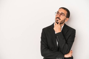 Beyaz arka planda izole edilmiş beyaz iş adamı şüpheli ve şüpheci bir ifadeyle yana bakıyor..