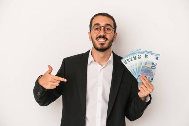 Beyaz arka plandaki insanlardan izole edilmiş, gururlu ve kendinden emin beyaz banknotlar tutan Kafkasyalı genç iş adamı.