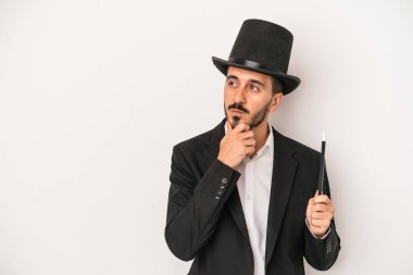 Beyaz arka planda asası olan genç sihirbaz şüpheli ve şüpheci bir ifadeyle yana bakıyor..