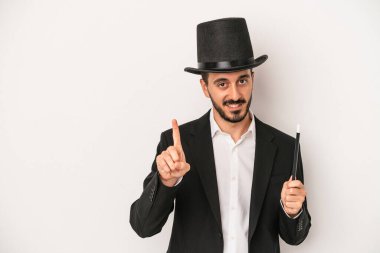 Genç sihirbaz sihirli değneği beyaz arka planda tutarken bir numarayı parmağıyla gösteriyor..