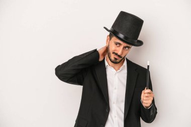 Beyaz arka planda asayı tutan genç sihirbaz başının arkasına dokunuyor, düşünüyor ve bir seçim yapıyor..