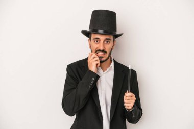 Genç sihirbaz sihirli değneği beyaz arka planda tutuyor tırnaklarını yiyor, gergin ve çok endişeli..