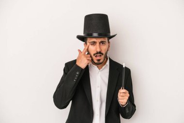 Beyaz arka planda asası olan genç sihirbaz işaret parmağıyla hayal kırıklığına uğramış..