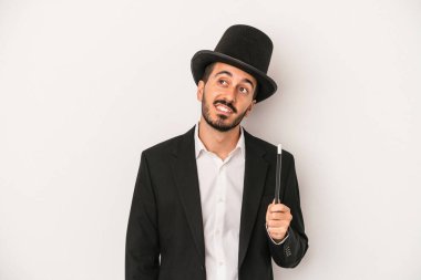 Genç sihirbaz sihirli değneği beyaz arka planda tutarak amaçlarına ve amaçlarına ulaşmayı hayal ediyor.