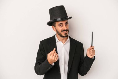 Genç sihirbaz sihirli değneği beyaz arka planda tutarak sanki seni davet ediyormuş gibi seni işaret ediyor..