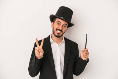 Genç sihirbaz sihirli değneği beyaz arka planda tutarken iki numarayı parmaklarıyla gösteriyor..