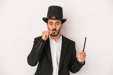 Genç sihirbaz sihirli değneği beyaz arka planda tutuyor parmakları dudaklarında bir sır saklıyor..