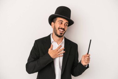 Beyaz arka planda asası olan genç sihirbaz elini göğsüne koyduğunda kahkahalar atıyor..