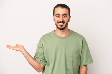 Beyaz arka planda izole edilmiş genç beyaz bir adam bir palmiye üzerinde fotokopi alanı gösteriyor ve belinde başka bir el tutuyor..