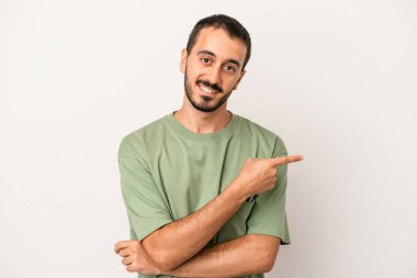 Beyaz arka planda izole edilmiş genç beyaz adam işaret parmağıyla işaret ederek gülümsüyor..