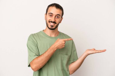 Beyaz arka planda izole edilmiş genç beyaz bir adam, palmiye üzerinde bir fotokopi alanı tutarken heyecanlı..