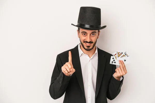 魔法のカードを持っている若い魔術師男は指でナンバーワンを示す白い背景に隔離されています — ストック写真
