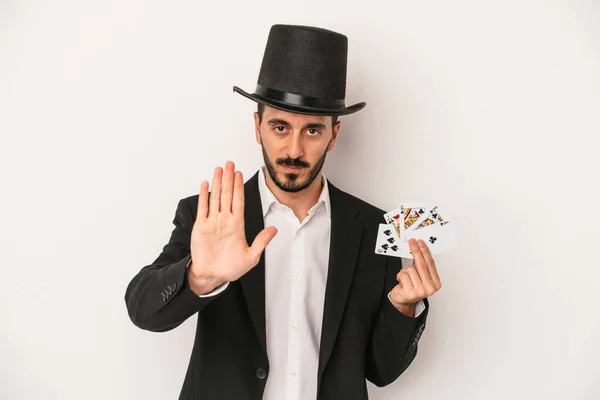 年轻的魔术师拿着一张白色背景的魔卡站在那里 伸出的手显示了停止的标志 阻止了你 — 图库照片