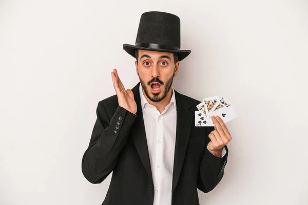 白い背景に隔離された魔法のカードを持っている若い魔術師の男は驚いてショックを受けました — ストック写真