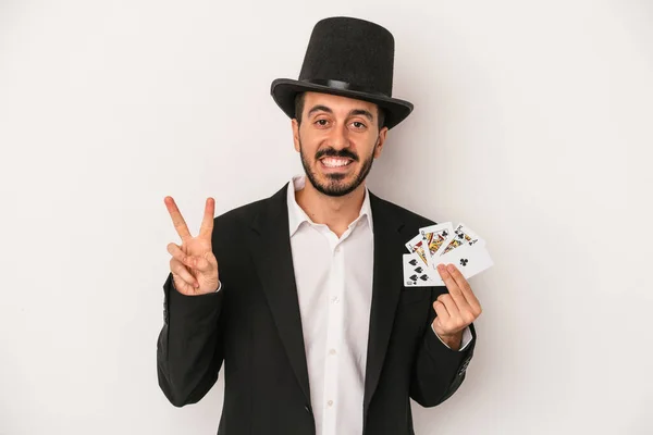 魔法のカードを持っている若い魔術師男は白い背景に隔離されています数字2と指 — ストック写真