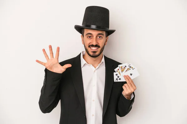 若いです魔術師男保持していますAマジックカード孤立した上に白い背景笑顔陽気に示す番号5とともに指 — ストック写真