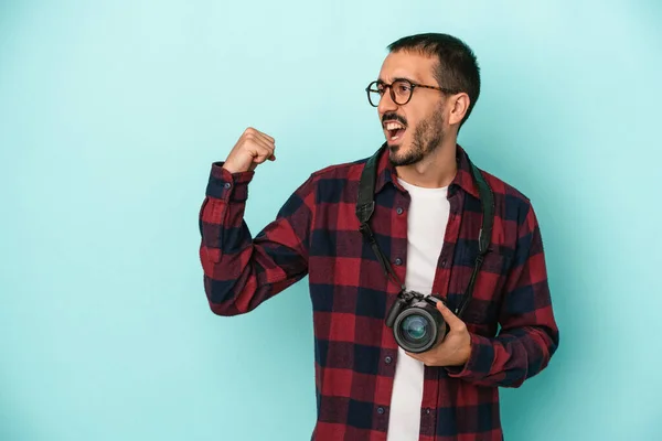 勝利の後に拳を上げる青の背景に隔離された若い白人写真家の男 勝者の概念 — ストック写真