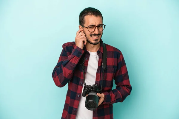 若い白人写真家の男は 手で耳をカバー青の背景に隔離 — ストック写真
