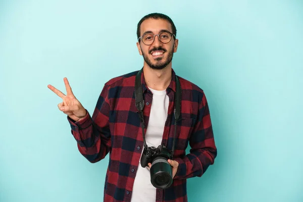 年轻的高加索摄影师 被蓝色背景隔离 快乐而无忧无虑 用手指展示和平的象征 — 图库照片