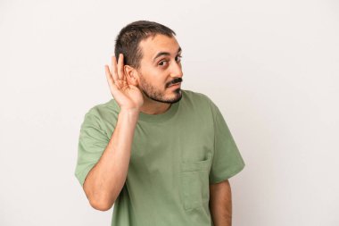 Beyaz arka planda izole edilmiş genç beyaz adam bir dedikoduyu dinlemeye çalışıyor..